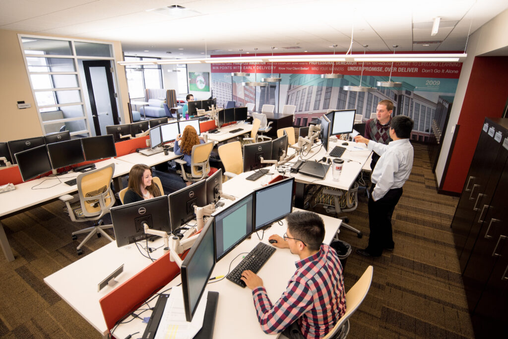 Interior office space with several employees working at desks with computer monitors