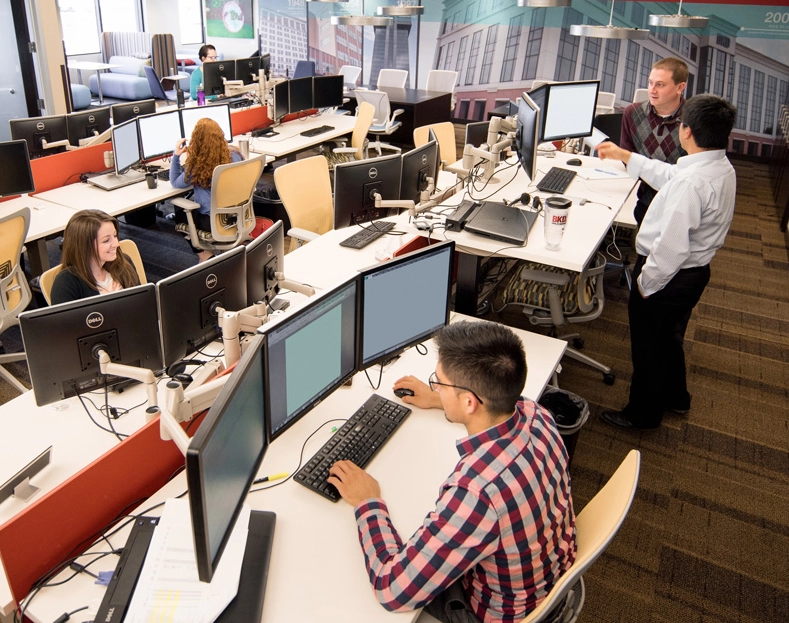Interior office space with several employees working at desks with computer monitors
