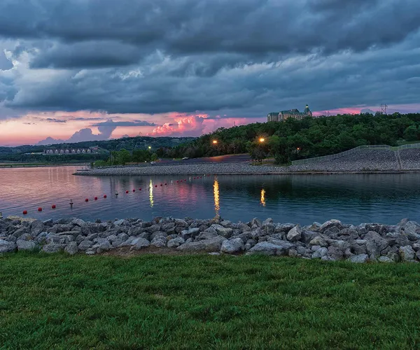 A dramatic, cloudy sunset on the shores of Table Rock Lake with a large hotel in the background