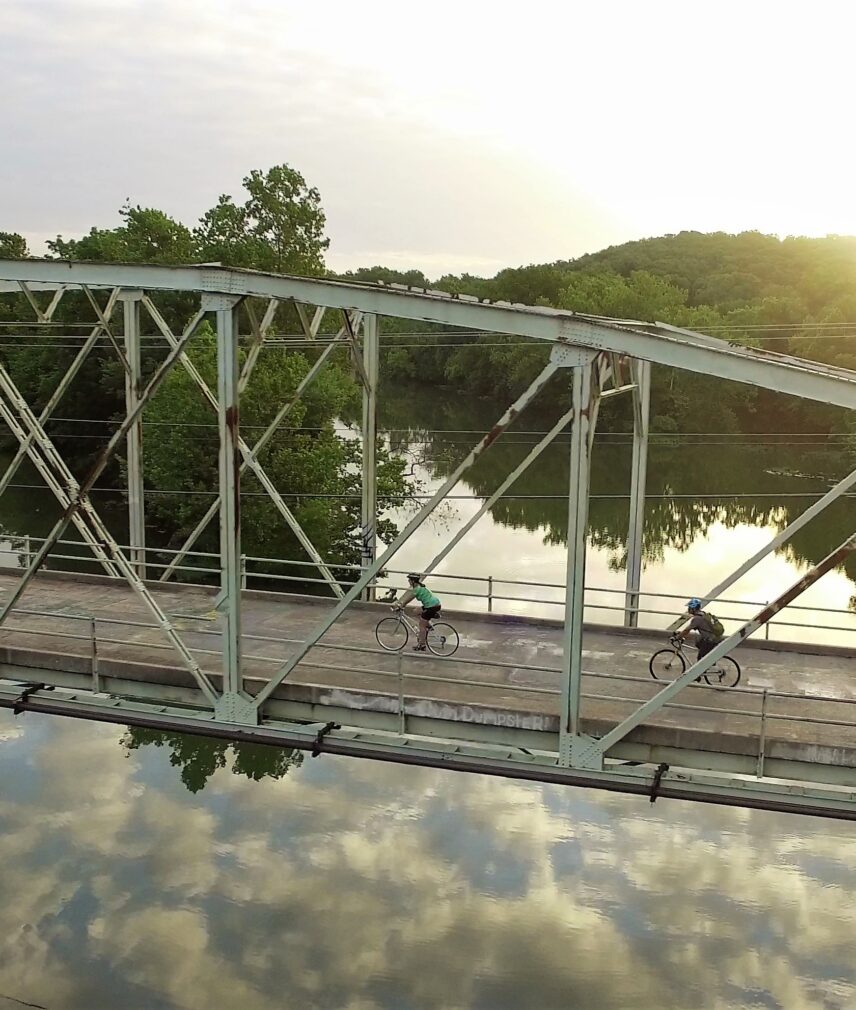 Tow bicyclists crossing an old metal bridge over Lake Springfield